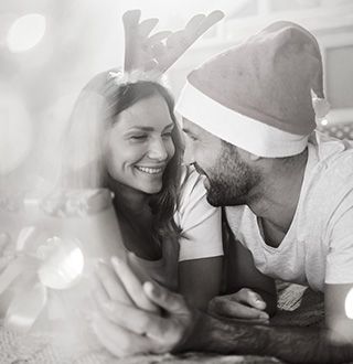 Couple homme femme en tenue de noël déballant des cadeaux