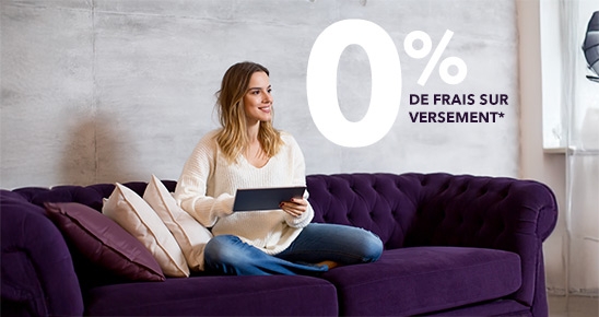 Femme souriante assise dans son salon avec sa tablette à la main en voyant "0% de frais de versement"
